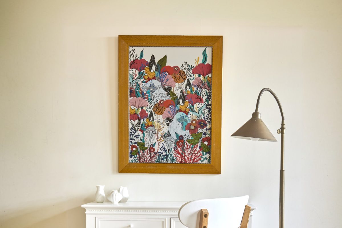Peinture de fleur avec un cadre bois, mis en contexte dans une pièce avec un bureau blanc et une lampe